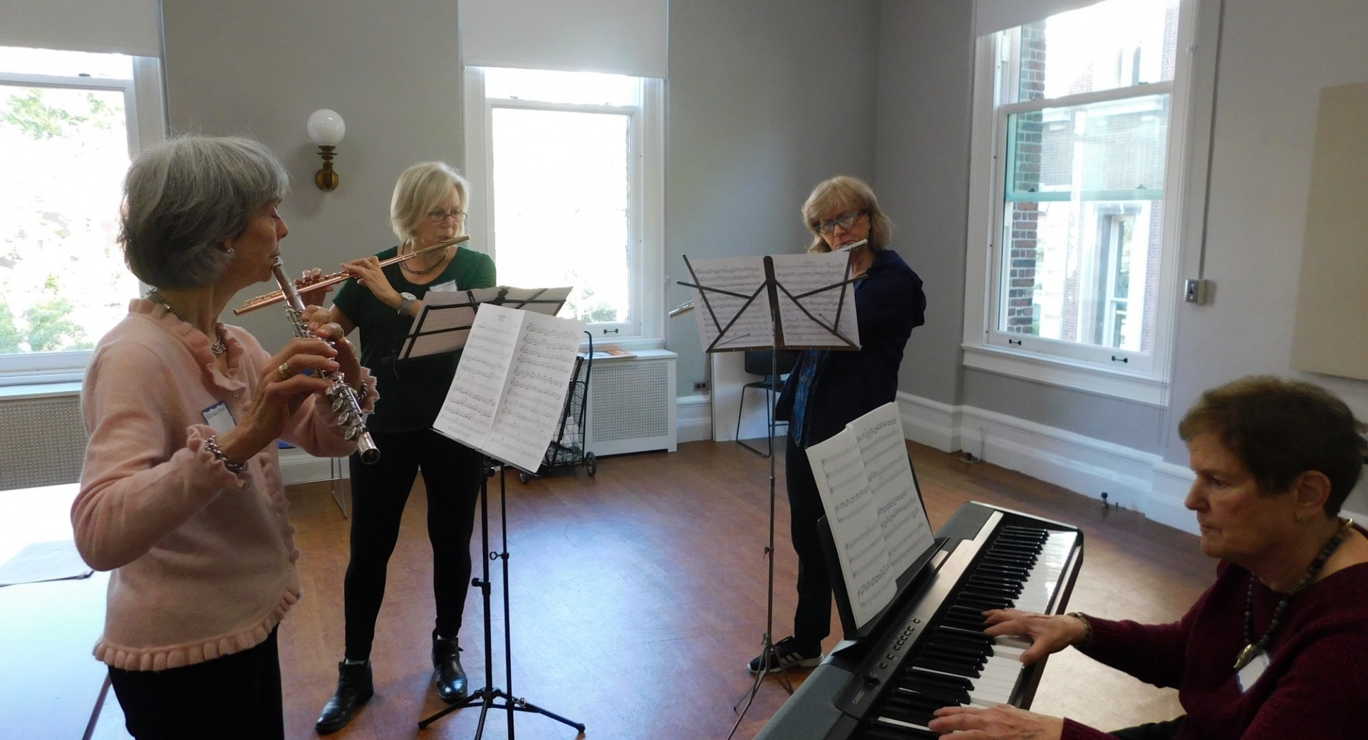 4 women playing instruments, flutes and keyboard